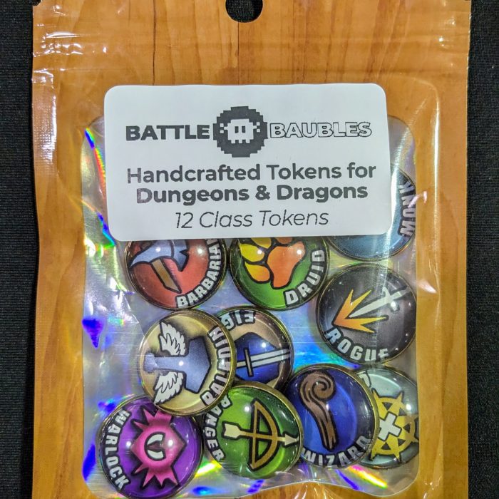 D&D Product Photo Package of ‘BATTLE BAUBLES Handcrafted Tokens for Dungeons & Dragons,’ featuring 12 colorful class tokens. Each token displays a unique symbol representing different D&D classes, such as a shield, an axe, and a spellbook. The packaging includes a clear plastic cover with a cardboard top displaying the product name and a pixelated image of a shield and crossed swords.